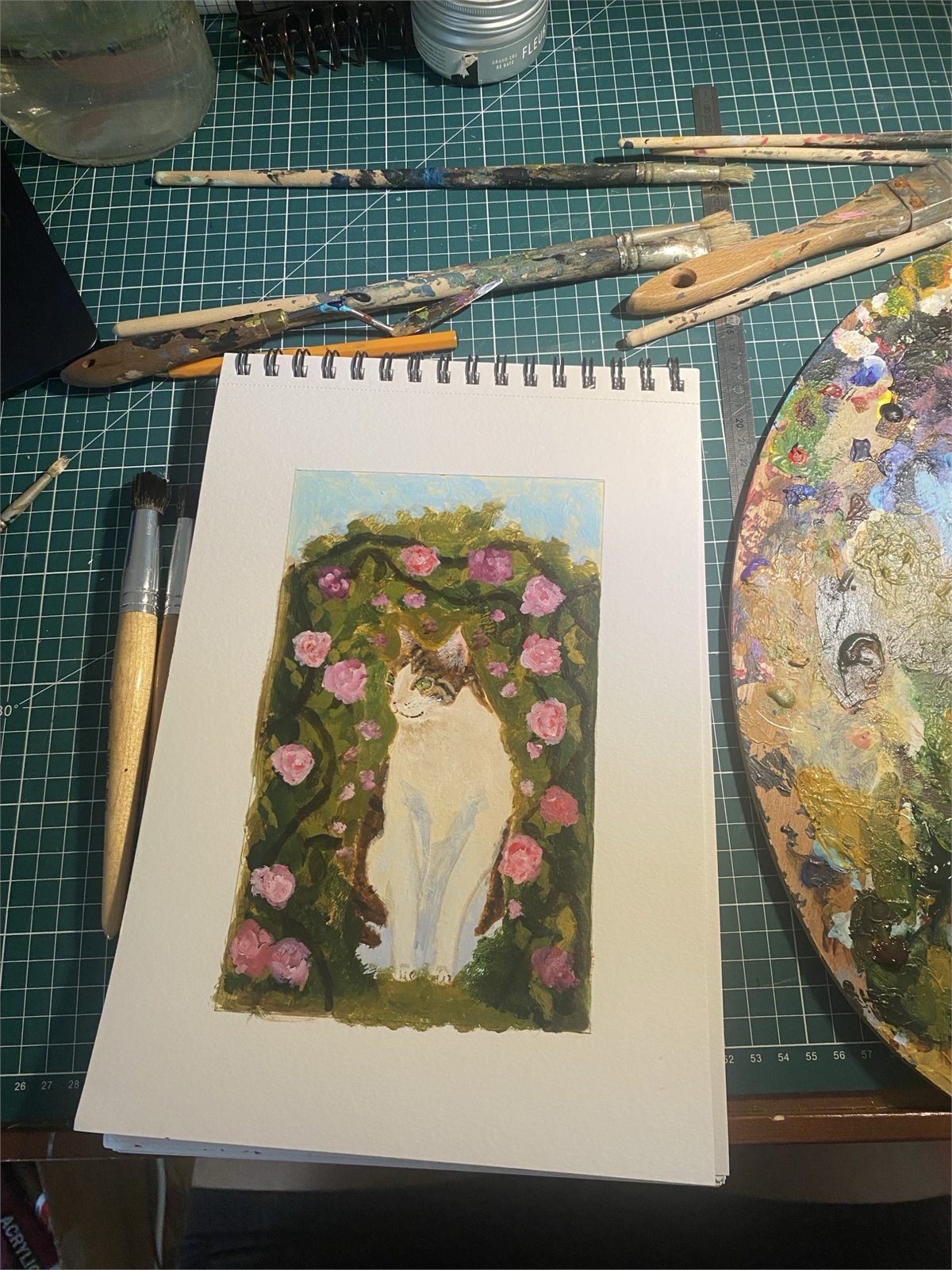 Sarah's hand-painted cat portrait surrounded by brushes and a paint palette